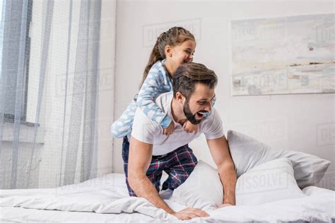 Loving father and cute daughter playing in bed